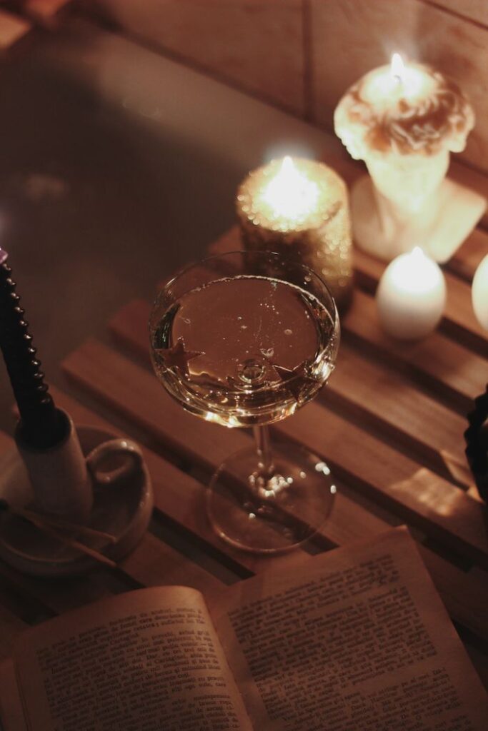Cozy scene with champagne, candles, and a book on a wooden caddy in a bathtub setting.