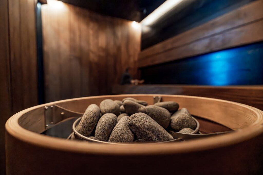 Cozy indoor sauna featuring dark wood, LED lighting, and a stone heater for a relaxing experience.