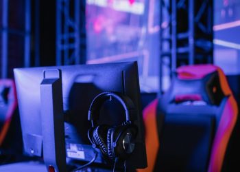 A modern gaming setup featuring a computer monitor and headset in a neon-lit environment.