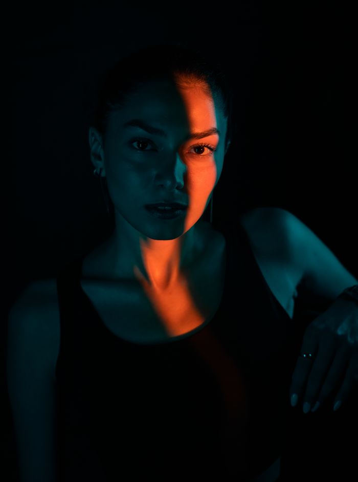 Striking portrait of a woman with dramatic lighting casting dynamic shadows and colors.